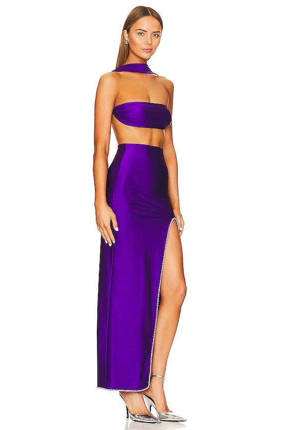 Woman wearing a purple halter neck dress with a slit on a white background