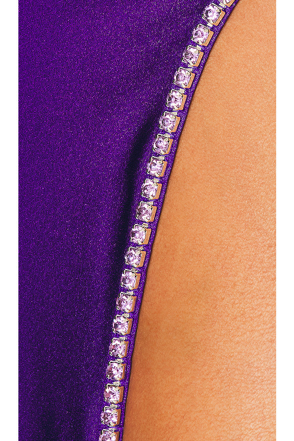Close-up of a purple garment with rhinestone detailing on a beige background