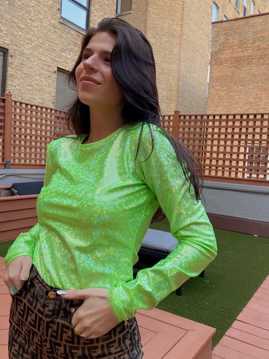 Woman wearing a bright green long-sleeve top outdoors on a deck.